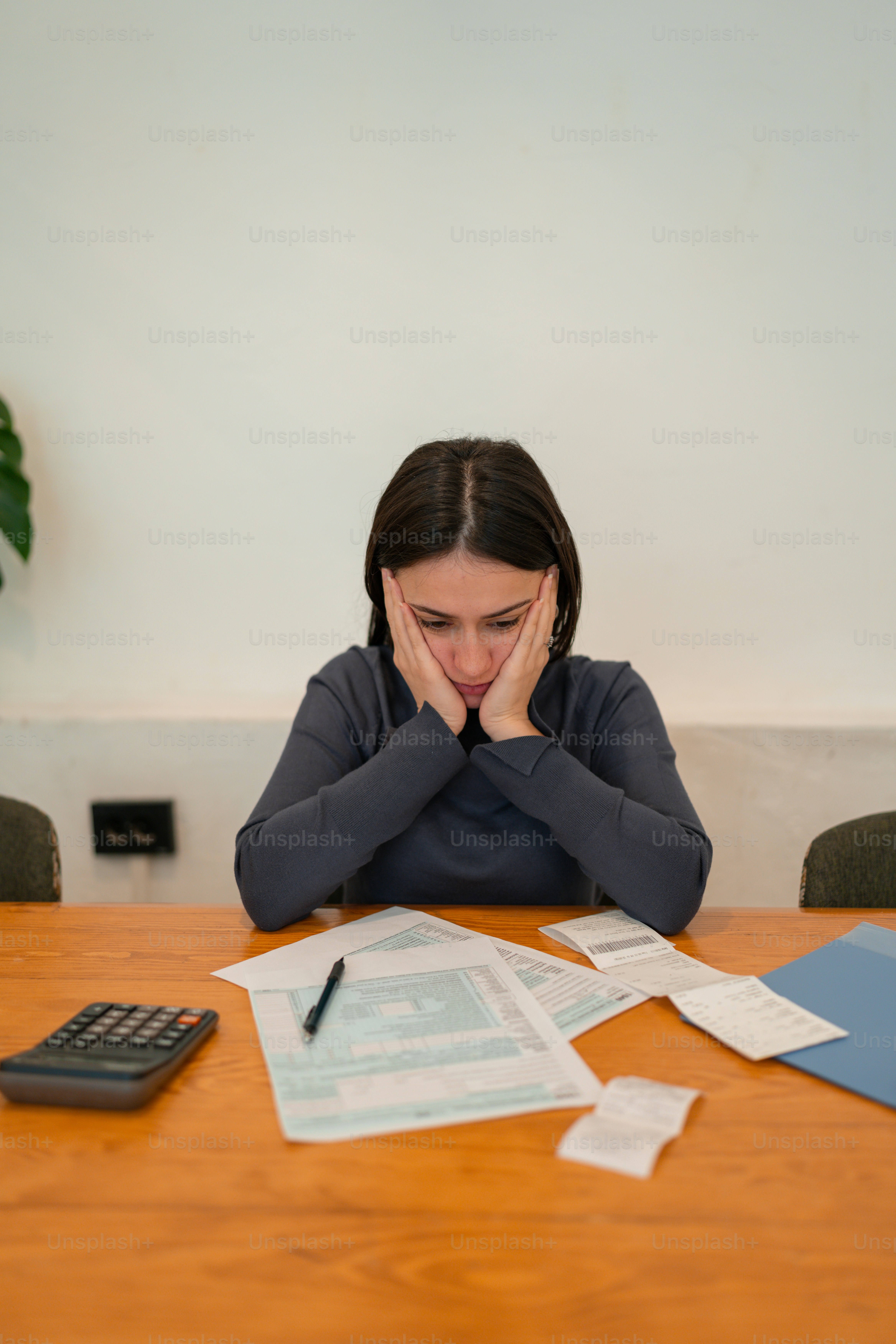 a woman sitting at a table with her hands on her face